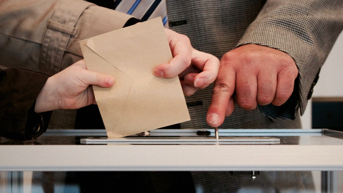 Alabama absentee ballots being placed into an official election ballot box slot