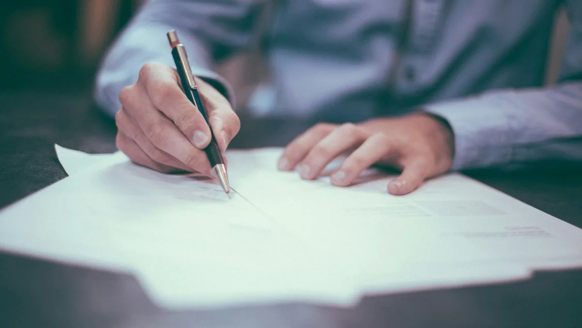 Person signing tax documents ahead of the EMS ISD VATRE on Nov. 3